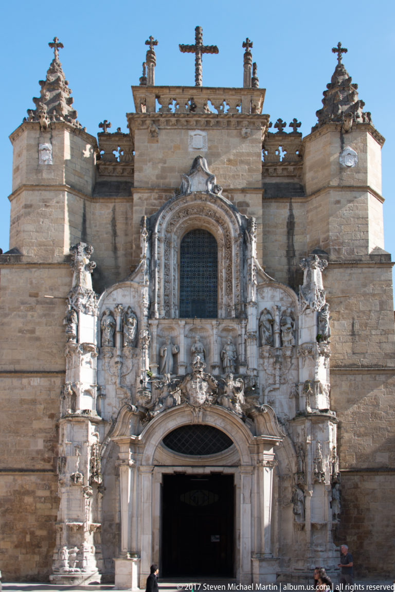 Close frontal view of the richly carved stone entrance and upper window of Santa Cruz Church in Coimbra.