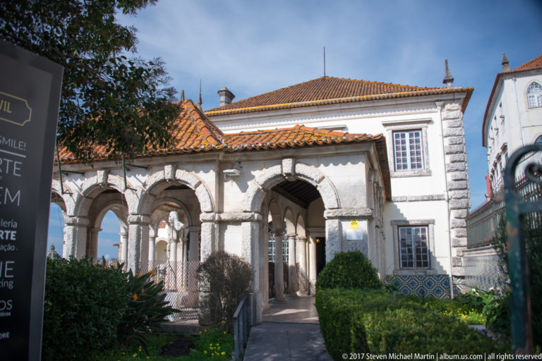 Arcaded Renaissance structure with tiled roofs, stone columns, garden path, and clipped shrubs at Coimbra’s Jardim da Manga.