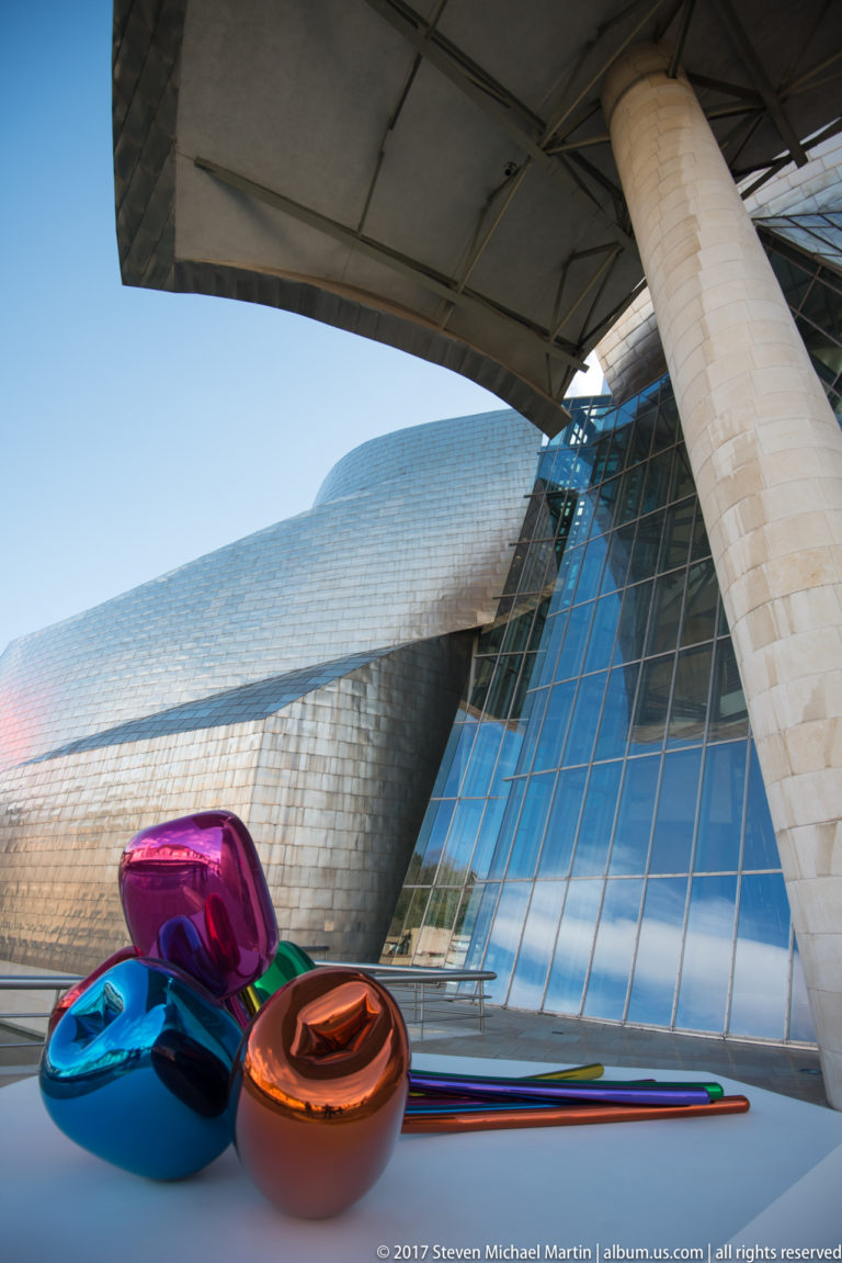 Jeff Koons’s colorful reflective Tulips sculpture on a terrace before the titanium and glass exterior of the Guggenheim Museum Bilbao.