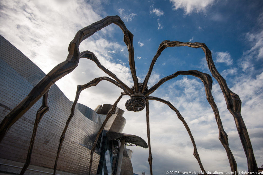 Louise Bourgeois’s giant spider Maman silhouetted against the sky with the curving Guggenheim Museum Bilbao exterior behind.