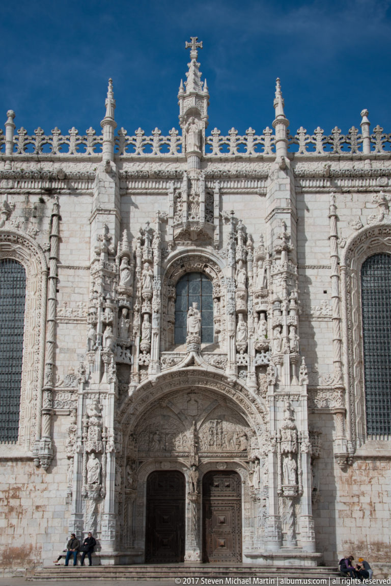 Richly sculpted south portal of the Jerónimos Monastery church with twin doors, saints, pinnacles, and elaborate tracery.