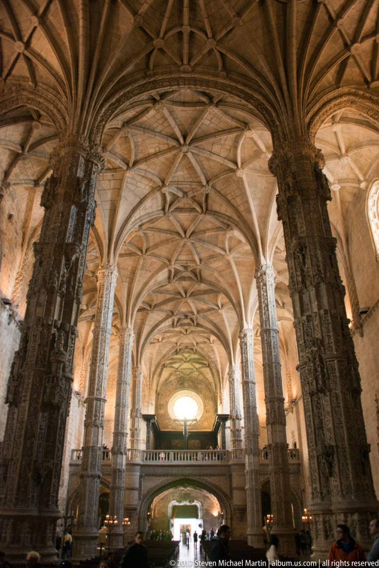 Jerónimos church interior looking toward the west gallery beneath soaring carved piers and intricate ribbed vaulting.