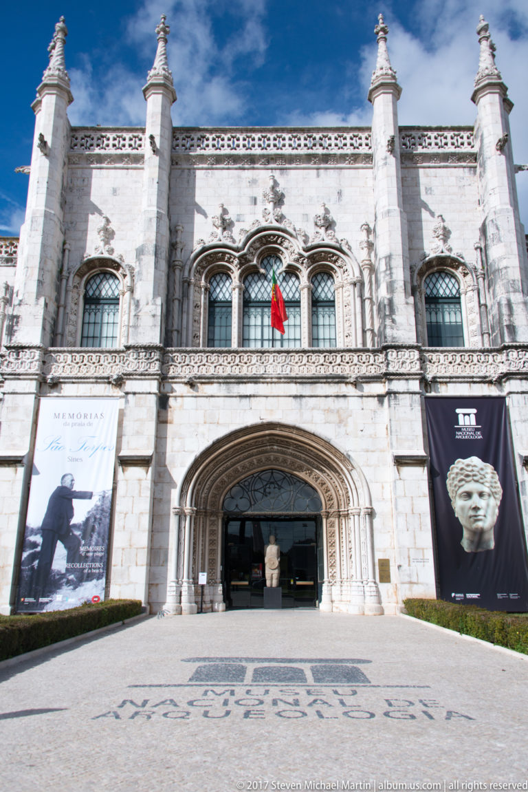 Entrance to the Museu Nacional de Arqueologia in the Jerónimos complex, with exhibition banners and arched stone portal.