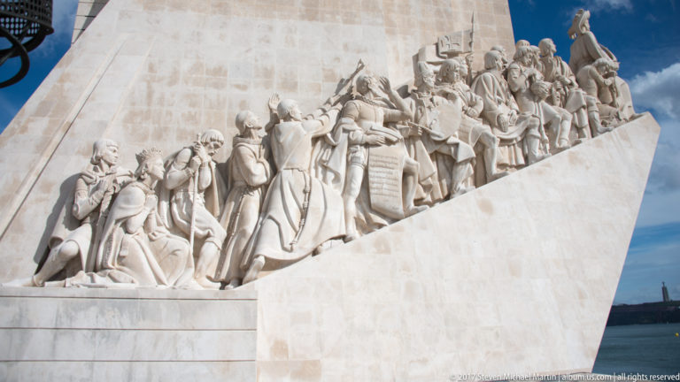 Close view of carved navigators, soldiers, clerics, and patrons grouped along the Monument to the Discoveries.