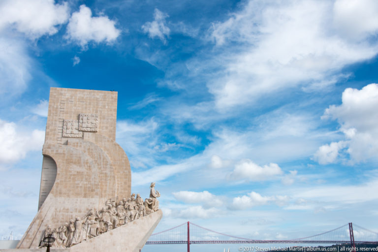 Monument to the Discoveries beside the Tagus with the red 25 de Abril Bridge stretching across the background.