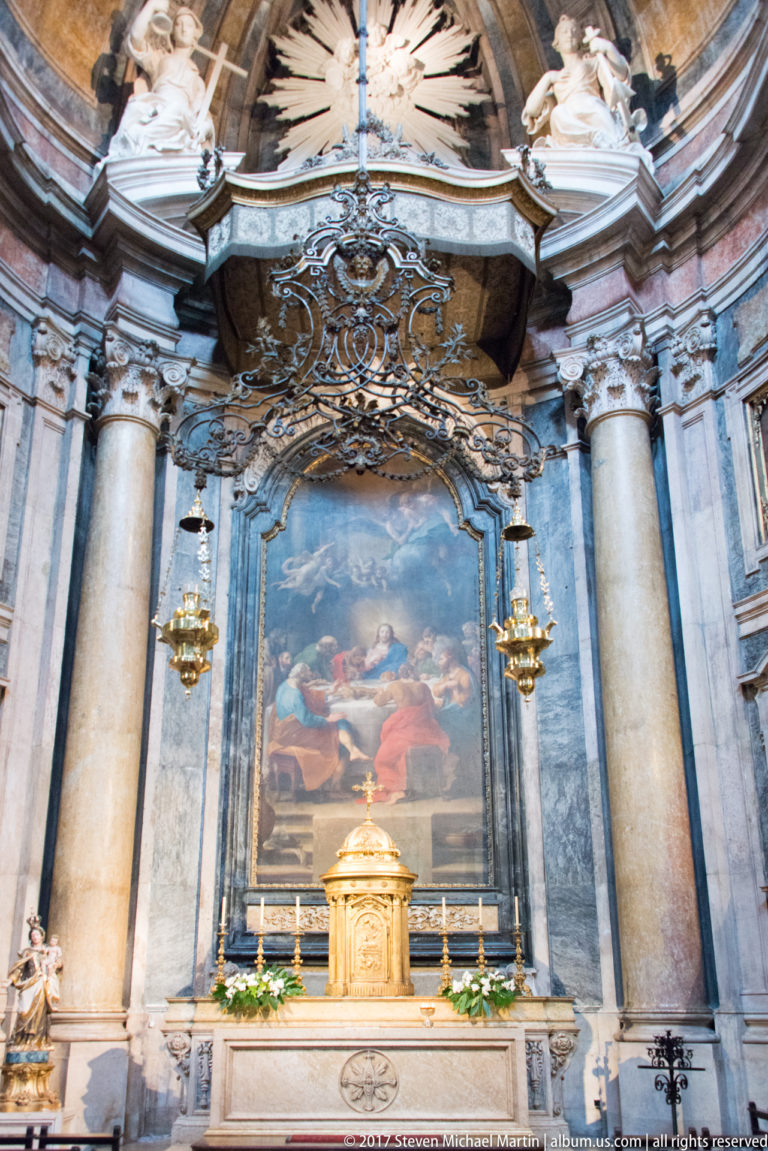 Marble altar with gilded tabernacle, large religious painting, hanging lamps, and monumental columns in the Basílica da Estrela.