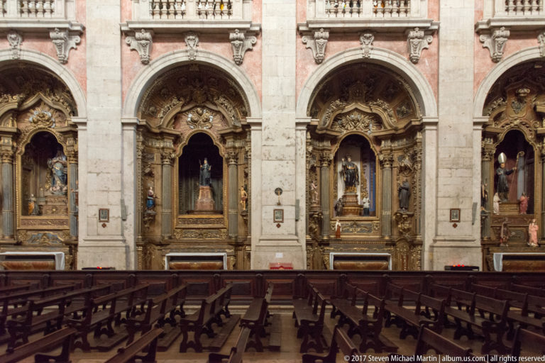 Row of ornate gilded side chapels with devotional statues above dark wooden pews inside a Lisbon church.
