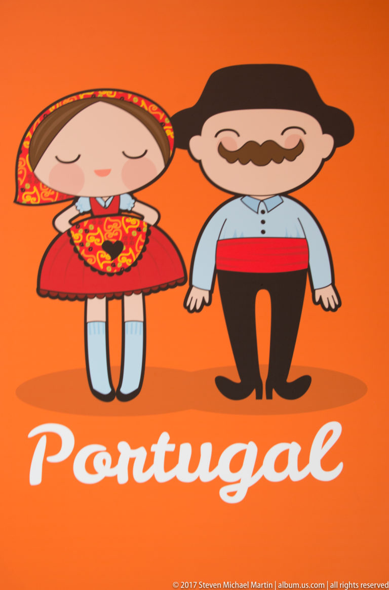 Orange souvenir graphic with cartoon Portuguese couple in traditionalized clothing and the word 'Portugal' in white script.