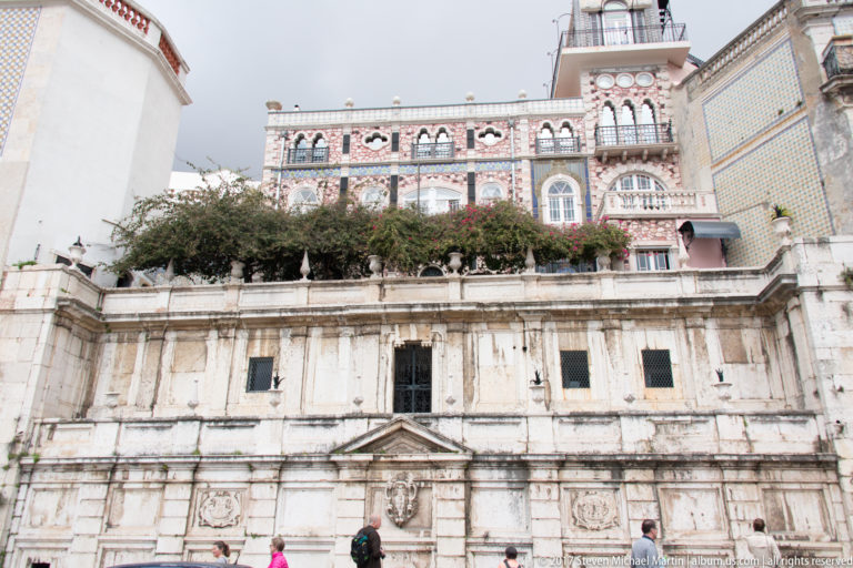 Stone Chafariz d'El-Rei in foreground with richly tiled Palacete Chafariz d'El-Rei rising behind.