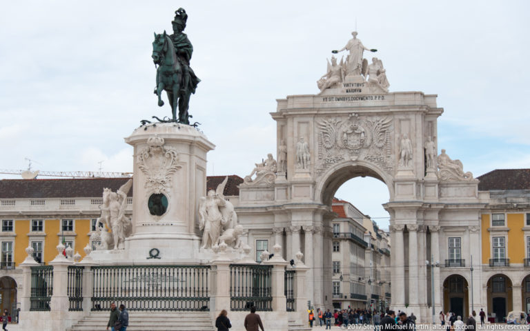 Equestrian statue of King José I before the white Arco da Rua Augusta and yellow arcades of Praça do Comércio.