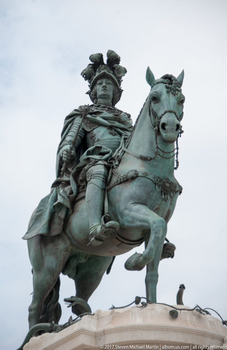 Close upward view of the bronze King José I in armor mounted on a horse with one foreleg raised.
