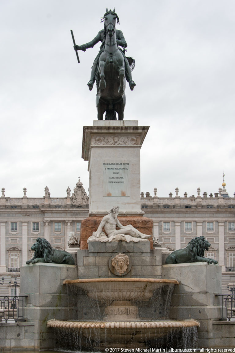 Equestrian statue of Philip IV on a tall pedestal above a fountain, with Royal Palace façade behind.