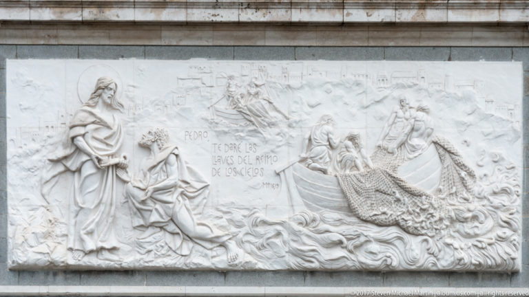 Stone relief with Christ, Saint Peter, other figures, and Spanish text about the keys, carved across a rectangular panel.