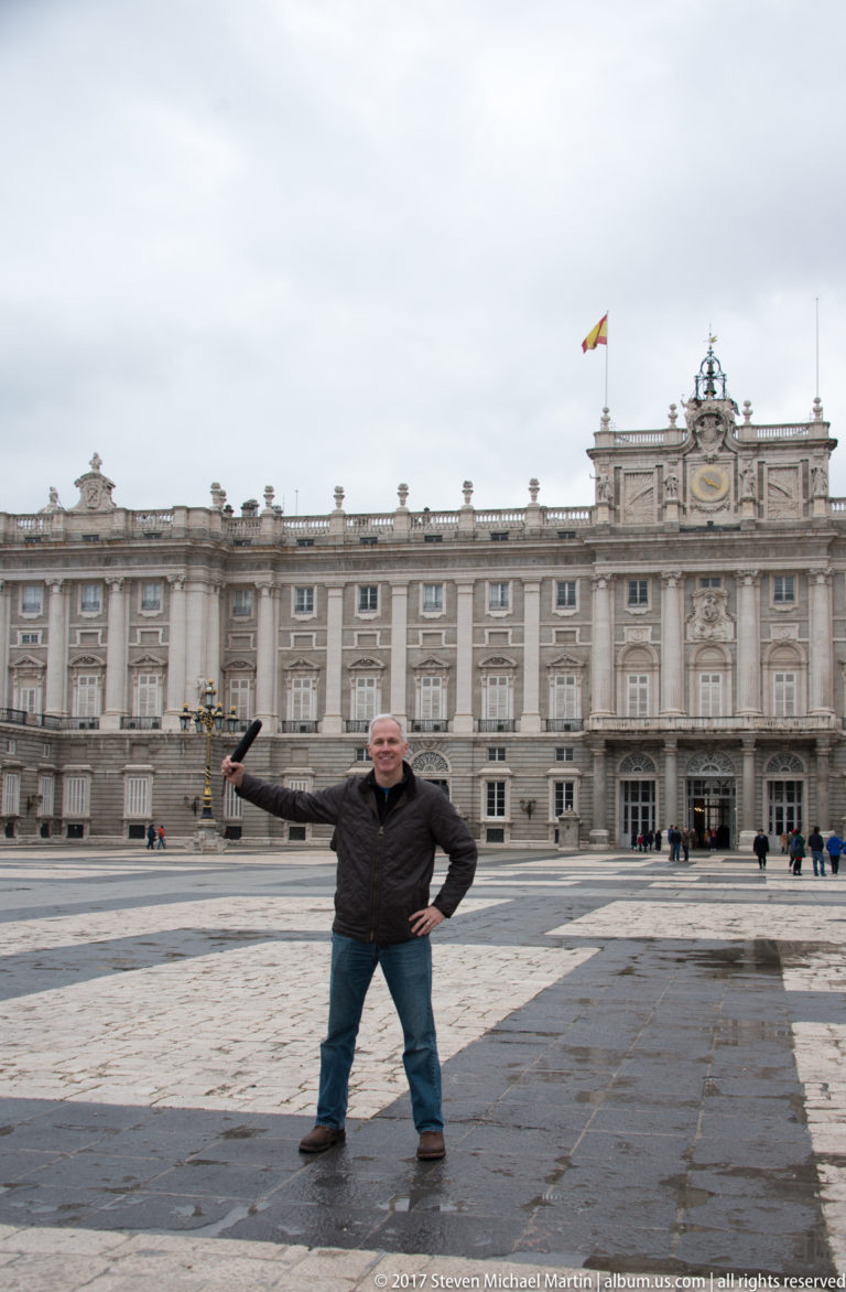 Visitor standing on the Plaza de la Armería before the long stone façade of Madrid’s Royal Palace.