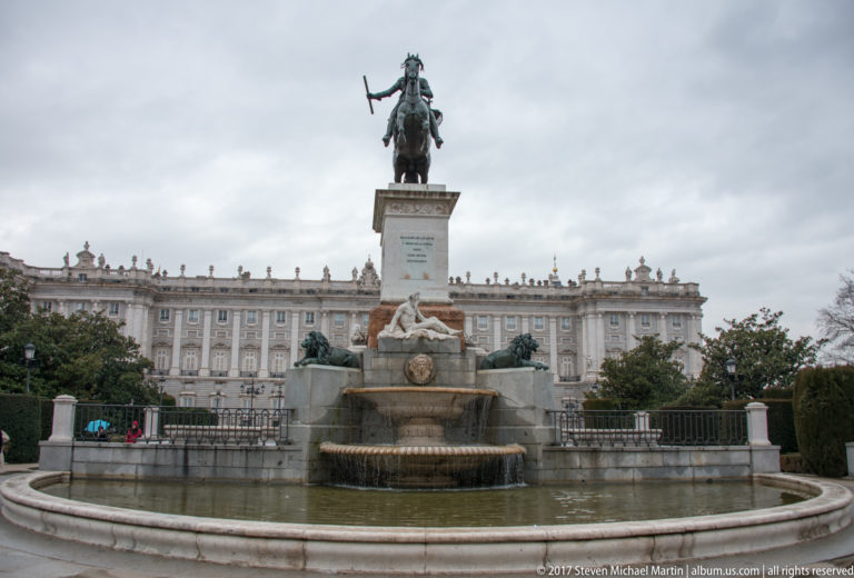 Wide view of the Philip IV equestrian monument and fountain in Plaza de Oriente, with the Royal Palace behind.