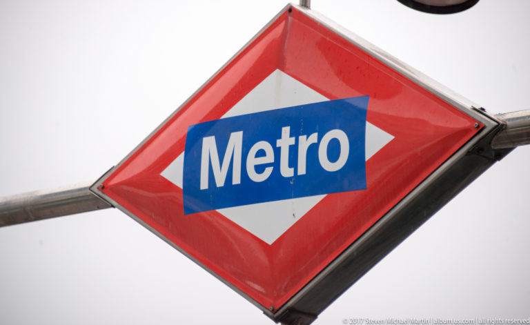 Close view of the blue Metro wordmark centered on Madrid’s red diamond-shaped transit sign.