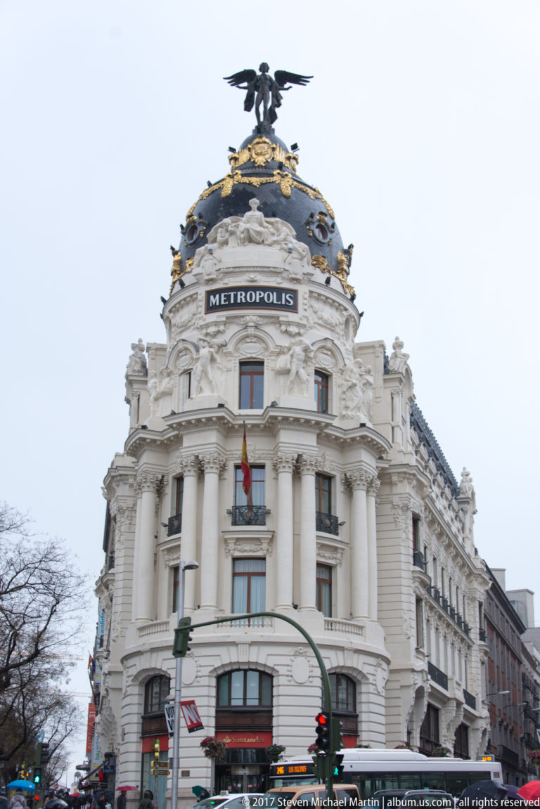 Ornate white Metropolis Building with dark domed roof, gilded decoration, winged rooftop figure, and METROPOLIS inscription.