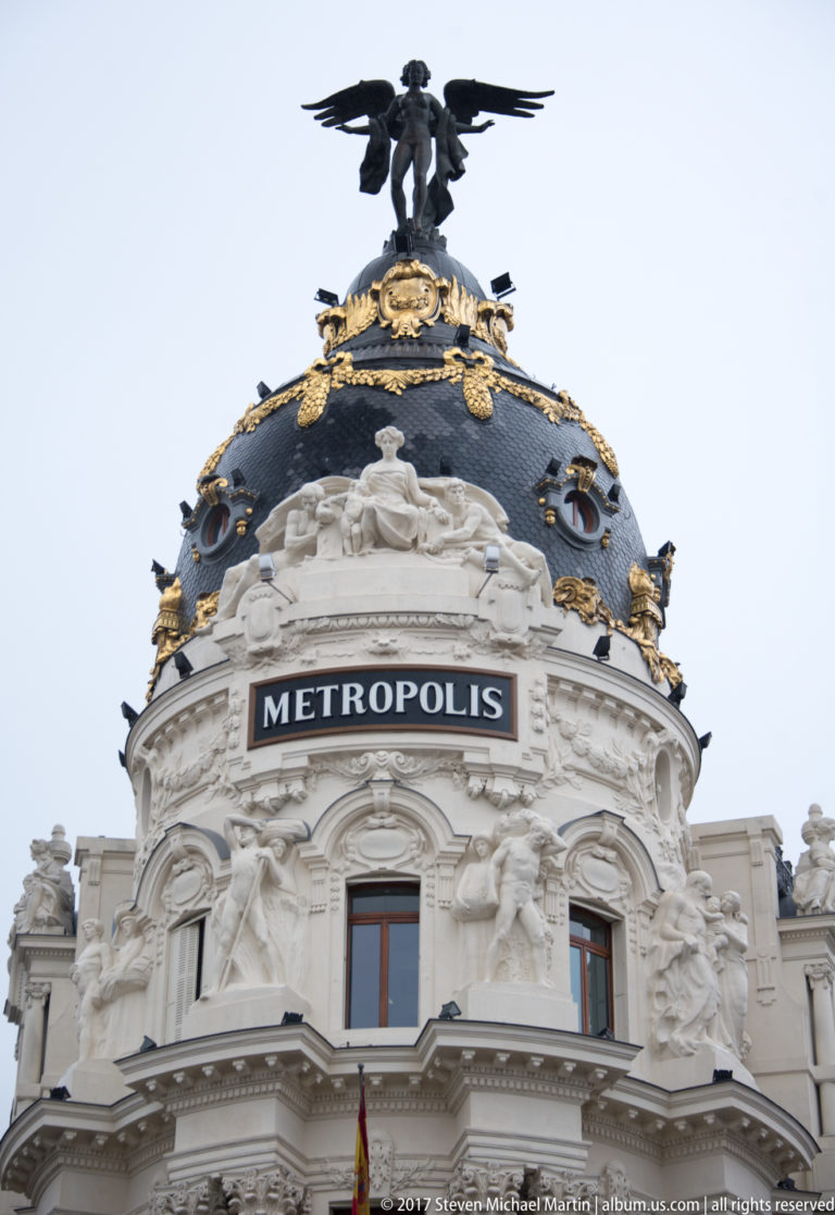 Ornate upper façade and black slate dome of the Metrópolis Building, crowned by a winged figure and gilded decoration.