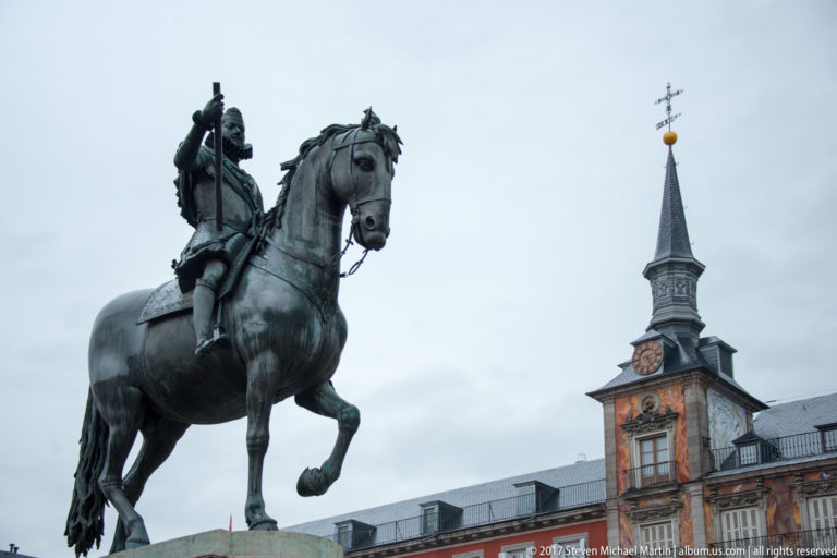 Philip III on horseback in Plaza Mayor, silhouetted against a clock tower of Casa de la Panadería.