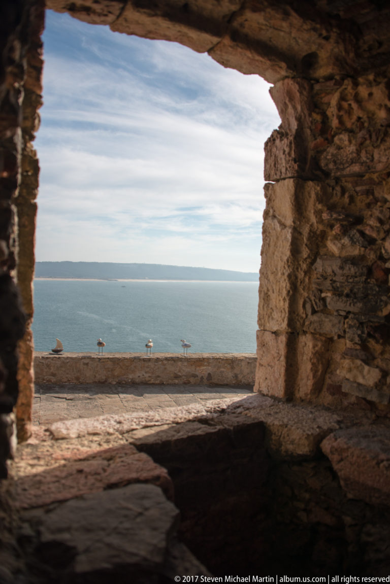 Blue Atlantic Ocean framed by a deep rough-stone opening in a thick fort wall.