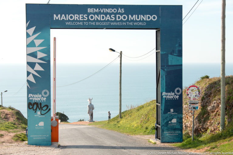 Road passing beneath a blue gateway reading Welcome to the Biggest Waves in the World.