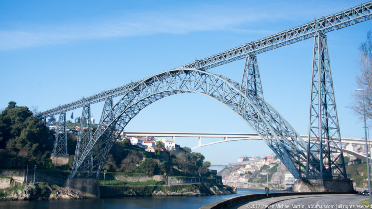 Lattice iron Maria Pia Bridge crosses the Douro on a high deck supported by a broad metal arch.