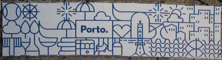 Close view of a blue line-art mural labeled “Porto.” with stylized buildings, trees, bridge forms and waves.
