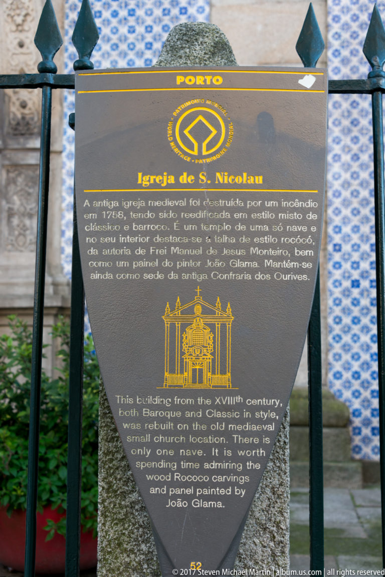 Interpretive sign for Igreja de São Nicolau standing in front of a blue-and-white azulejo-covered wall in Porto.