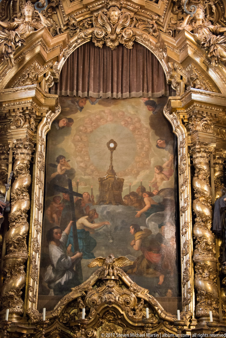 Large religious painting framed by elaborate gilded carving and sculptural ornament inside Igreja de São Nicolau in Porto.