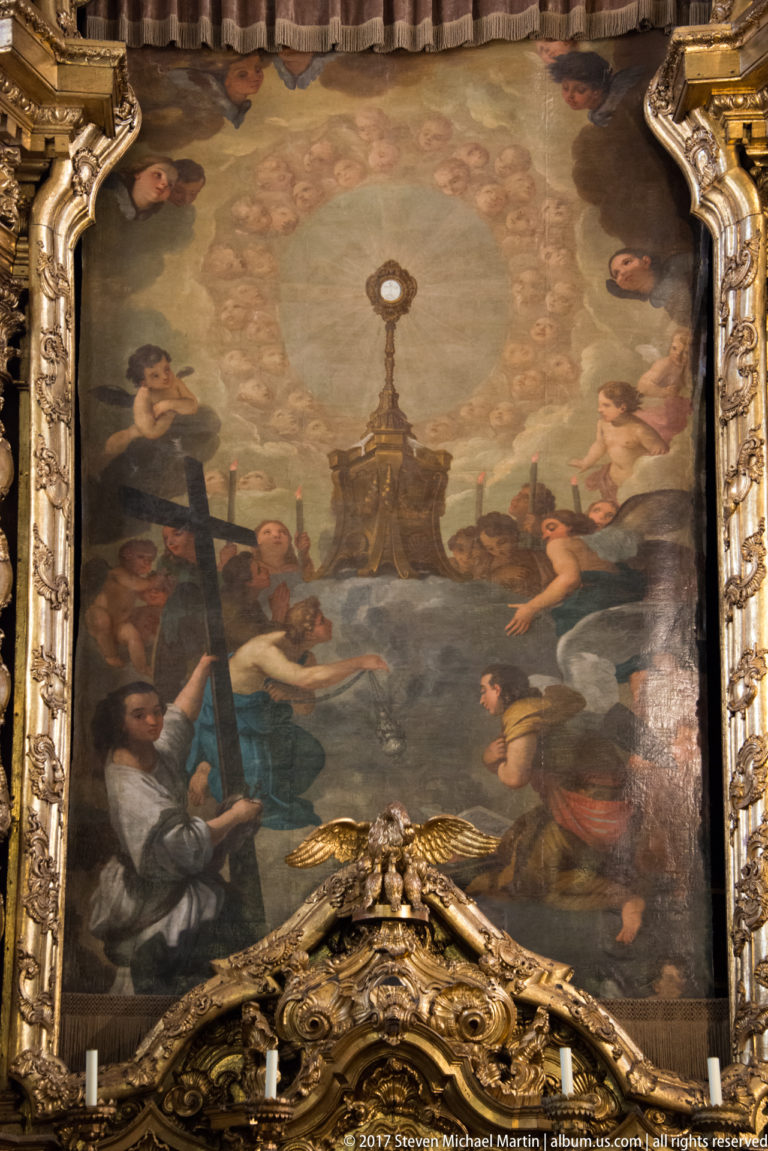 Closer view of a large multi-figure religious painting above projecting gilded carving inside Igreja de São Nicolau.
