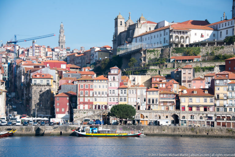 Dense colorful buildings rise from Porto’s Ribeira quay above a riverboat on the Douro.