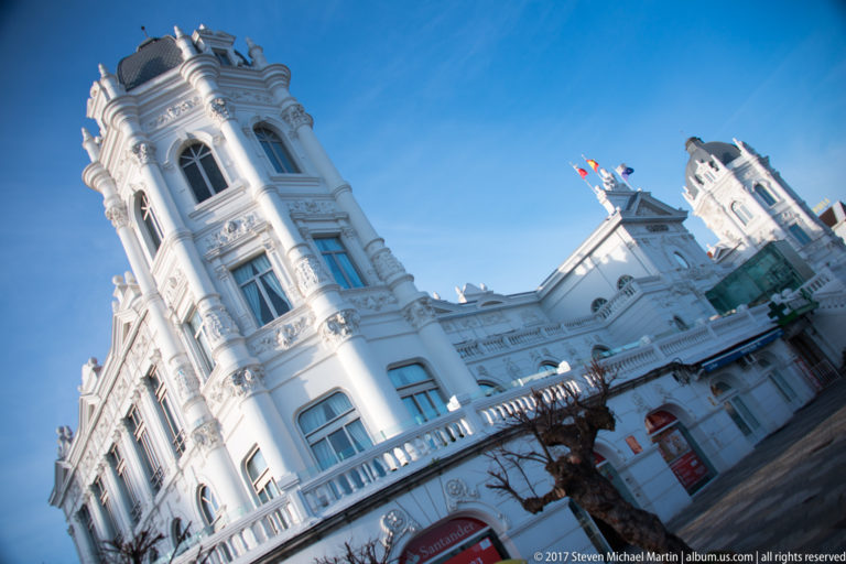 Canted view of ornate white Gran Casino del Sardinero façades with rounded bays, tall windows, and balustrades.