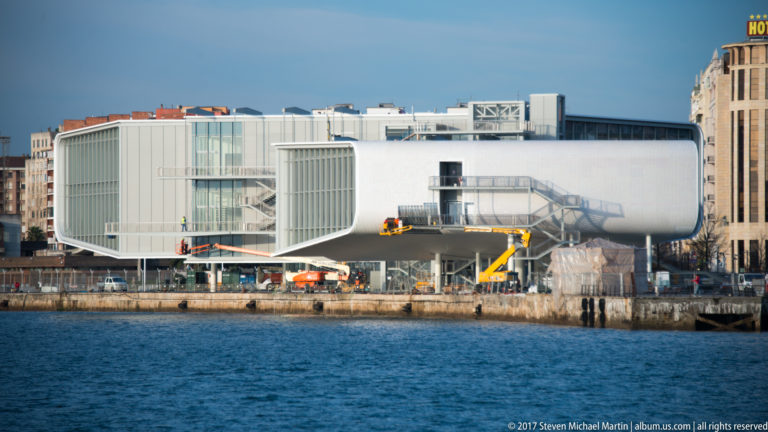 Centro Botín on Santander waterfront, with elevated rounded white volumes, glazed ends, exterior stairs, and harbor water.