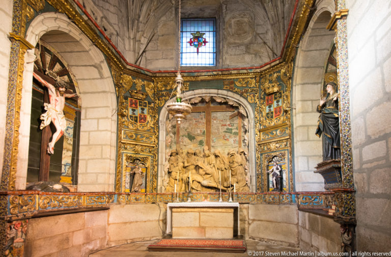 Colorful side chapel with a central sculptural relief, gilded painted panels, flanking saints, and a small altar.