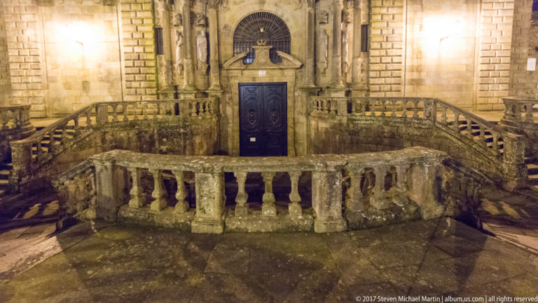 Curved granite balustrades and steps forming a ceremonial approach to a church doorway at night.