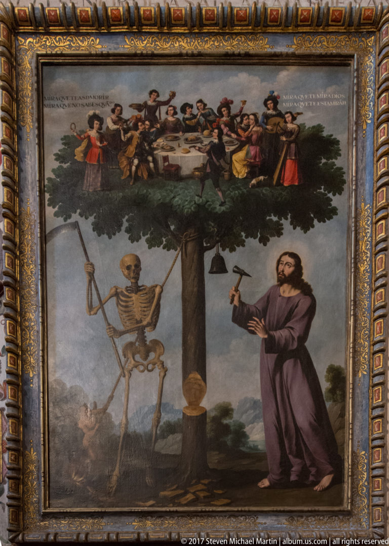 Framed allegorical painting showing a bearded man with an axe, a skeleton, a partly cut tree, and people gathered in its crown.