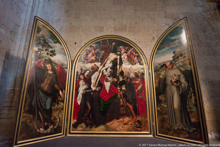 Three-panel religious painting with mourners around the dead Christ in the center and devotional figures on narrower side wings.