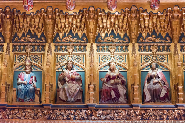 Four seated polychrome royal figures appear in adjacent niches within an ornate gilded wooden arcade with blue panels and carved tracery.