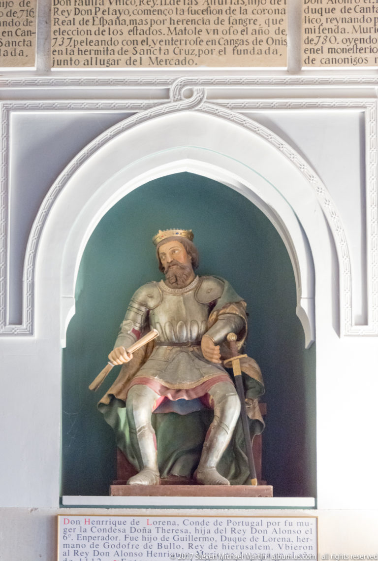 Seated crowned king holding a sword across his lap in a white arched niche, with inscription panels above and below.