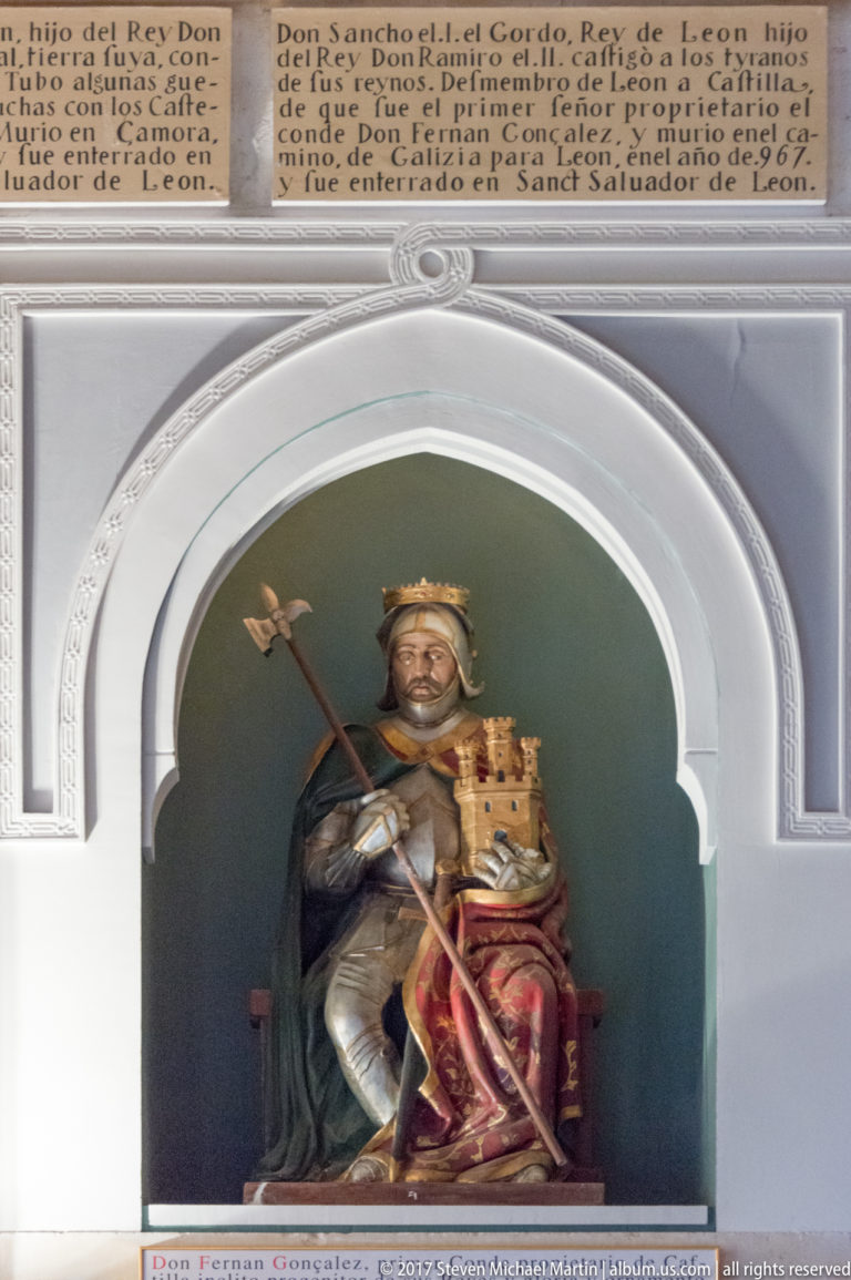 Seated crowned ruler holding a long staff beside a smaller crowned figure in a white arched niche with Spanish labels.
