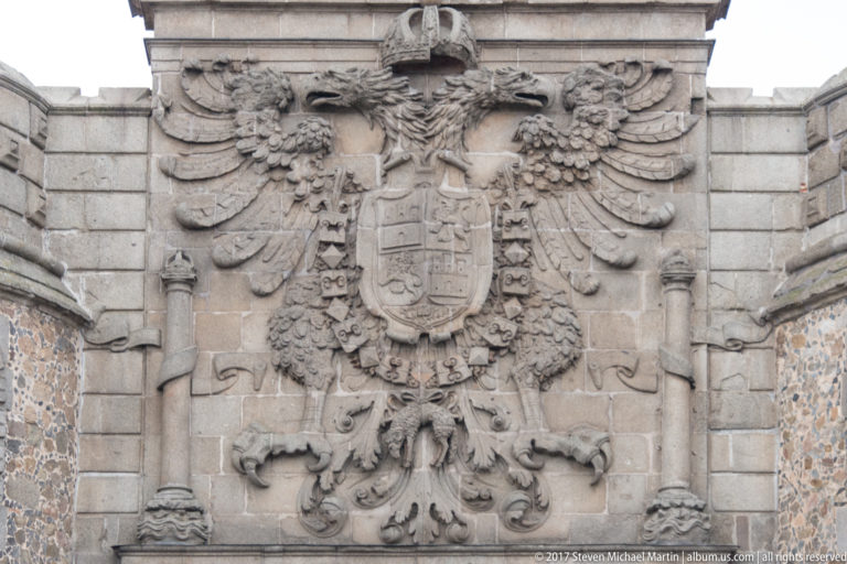 Large carved stone double-headed eagle supporting a crowned royal shield with chains and elaborate heraldic ornament.