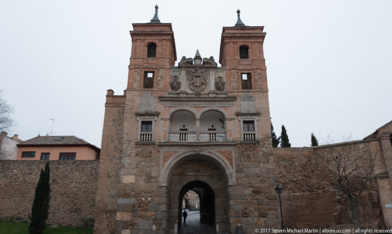 Inner façade of Puerta del Cambrón with deep central arch, paired upper openings, heraldry, square towers, and adjoining wall.
