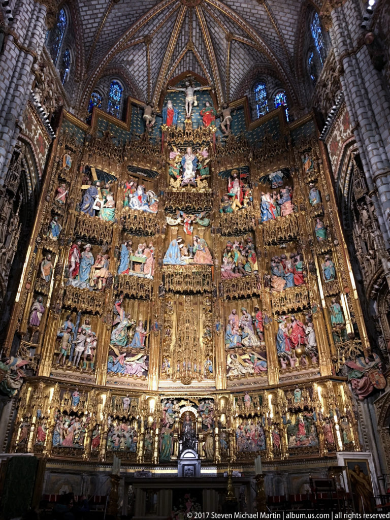 Monumental gilded Gothic retablo filling Toledo Cathedral’s sanctuary with tiers of colorful narrative scenes and carved figures.