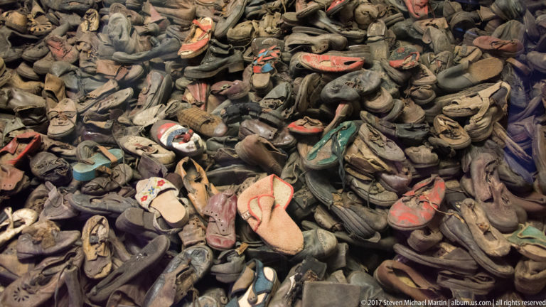 Large pile of worn adult and children’s shoes in varied styles and faded colors at the Auschwitz museum.