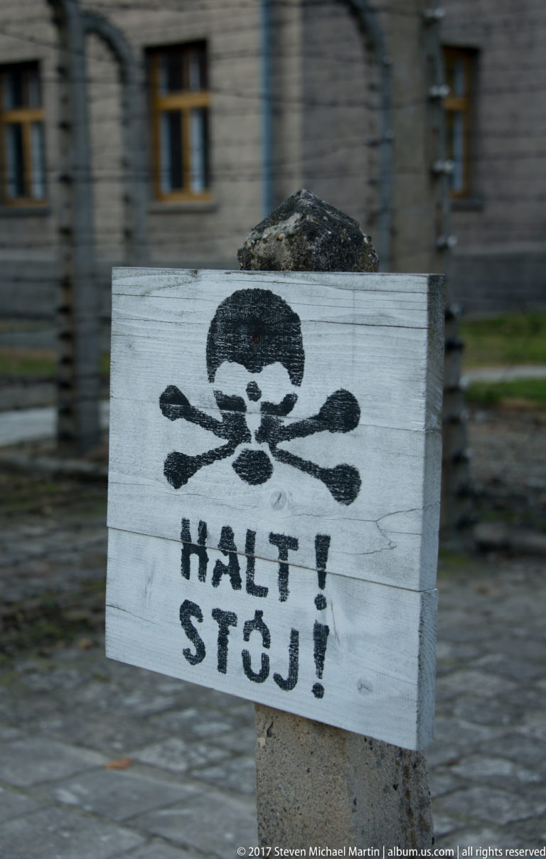 Close view of a pale warning board painted with skull and crossbones and the words “HALT! STÓJ!”