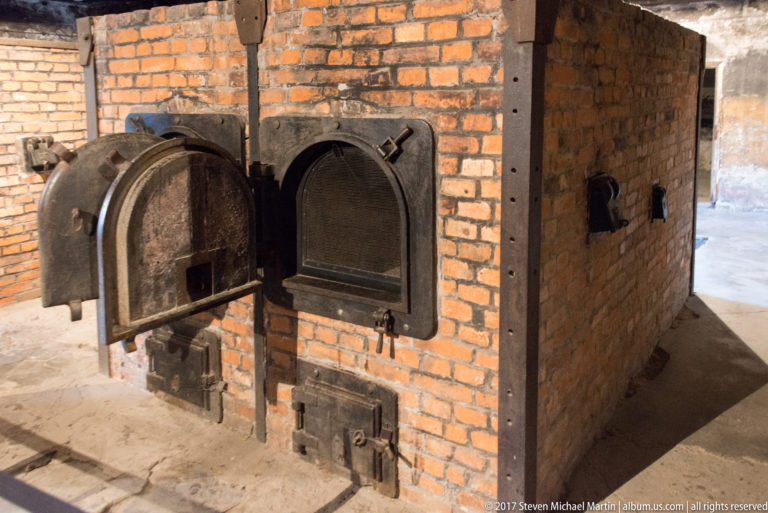 Brick cremation ovens with large arched iron furnace doors and smaller ash doors inside Auschwitz I Crematorium I.