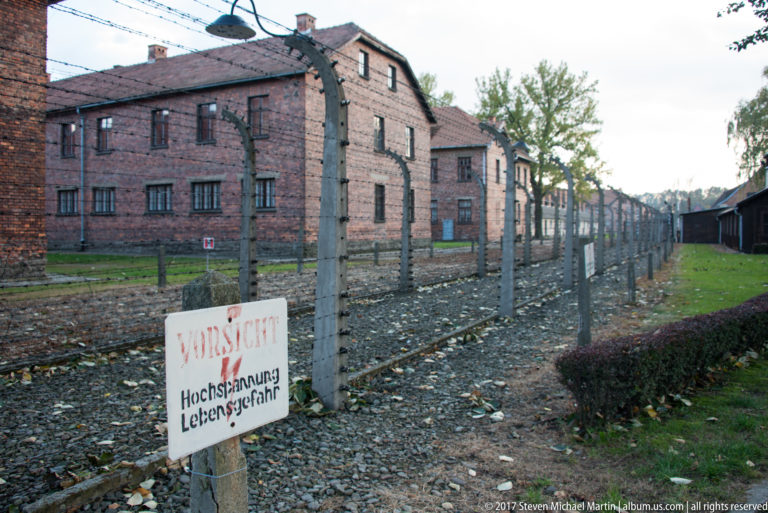 German “Vorsicht! Hochspannung Lebensgefahr” high-voltage warning sign beside the Auschwitz I electrified fence.
