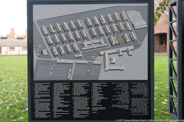 Large gray site map of Auschwitz I with numbered buildings and a multilingual legend beneath.