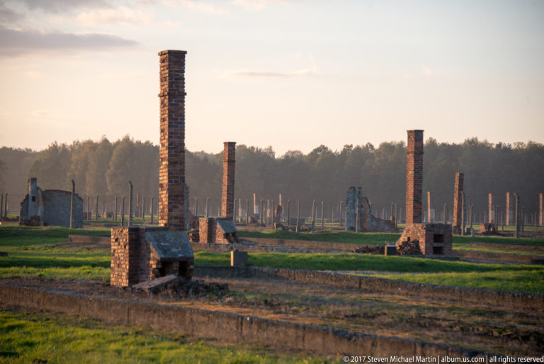Freestanding brick chimneys and low foundations marking former barrack rows at Auschwitz II-Birkenau.
