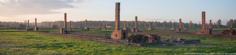 Brick chimneys, low foundations, and collapsed masonry among the former barracks at Auschwitz II-Birkenau.